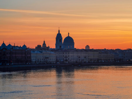 Golden spring sunset in the city. Saint Petersburg cityscape over Neva River in Russia. City skyline colorful photo with historical Russian architecture. Postcard view of the city.の写真素材