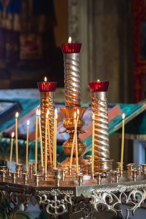 Church candles are burning on a large golden vintage candlestick in the orthodox church. Christian faith and tradition. Theme of faith and God, religion and traditions. vertical view.の写真素材