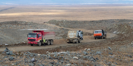 Trucks on a mountain road, road work on a new mountain highway. Construction of a new road to remote mountainous areas. Panoramic view.の写真素材