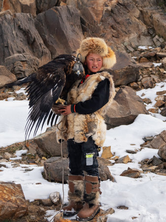 Ulgiy, Mongolia - September, 30, 2023: Northern Mongolia. Portrait of a boy with a hunting golden...