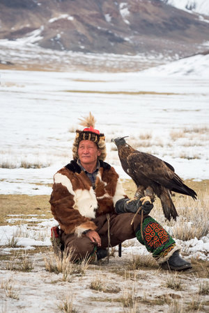 Ulgii, Mongolia - October, 01, 2023: Portrait of an experienced male hunter with a hunting golden...