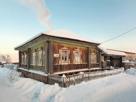 Winter in the Russian countryside. Ancient wooden hut under the snow. Rural life and way of life preserved to the present day. Winter street in the village of Cherdyn, Perm region. Russia.の写真素材