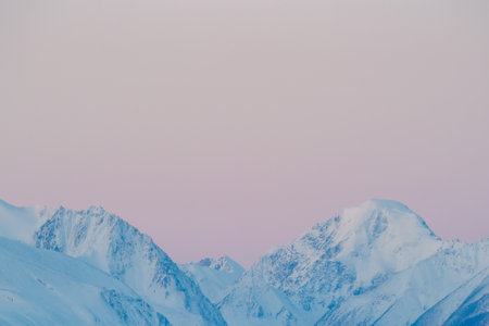 Pink colored mountains by the morning light at the Altai mountains. Sunrise reflection on a snow mountains. Mountain peaks with morning light. Copy space.の写真素材