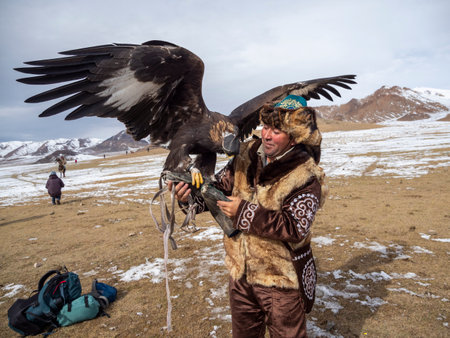 Ulgii, Mongolia - September, 30, 2023: Portrait of an experienced male hunter with a hunting golden eagle at a competition. Eagle hunters are people who train and hunt with golden eagles in Mongolia.のeditorial素材