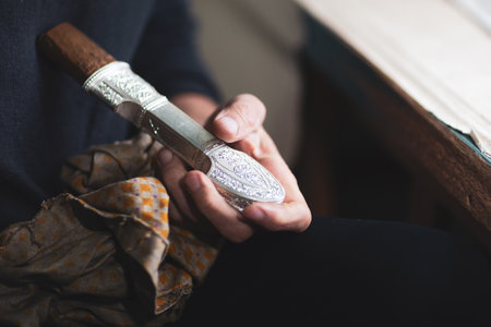 Selective focus. The hands of the Kubachin jewelry masters hold an silver dagger handle, close-up....