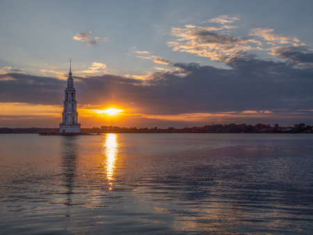 Stunning sunrise over the bell tower on the island, minimalistic view. Kalyazin flooded orthodox church on Volga river in Russia. Bell tower in the lake. Cruise along the Volga river.の写真素材
