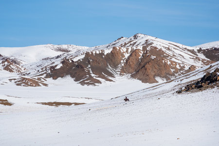 Horseman on white snowy mountain slope. Beautiful Mongolian winter landscape snow mountain with a...