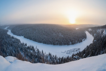 Top view of a frozen river in a snowy wooded rocky canyon. Beautiful sunrise on a frosty morning, a snowy cliff, trees on the edge. Winter on the. Nature landscape winter forest frostedの写真素材