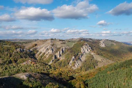 On top of the mountain, above the forest. Crimean mountains. A wide mountain range under a blue sky with white clouds.の写真素材