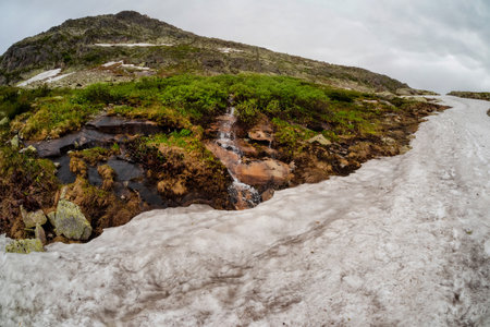 Mountain difficult track through glacier, stones, cobblestones, moss with a unique landscape. Landscape photography of snow and stone river with snow in summer time.の写真素材