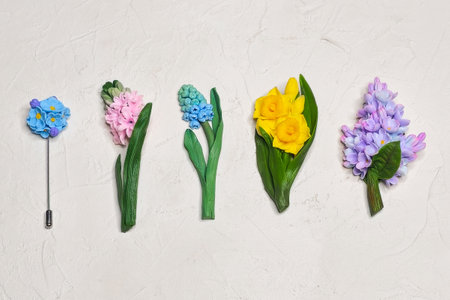 Variations of brooches in the form of flowers forget-me-not, hyacinth, muscari, narcissus and lilac on a white. Woman fashion jewelry accessory. Art product made of baked polymer clay.の写真素材
