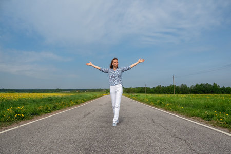 Happy woman running on country road in summer. Free space. Liberty, peace of mind concept.の写真素材