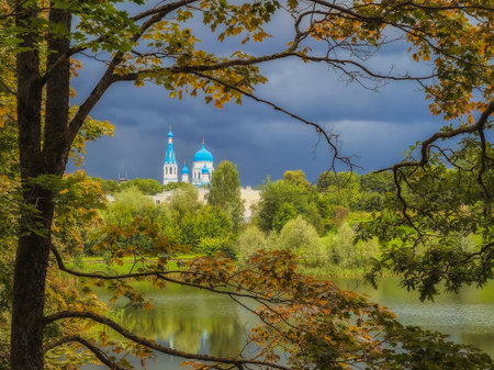 White Cathedral in the distance surrounded by golden autumn trees. Gatchina old city park. View through the branches of a tree.の写真素材