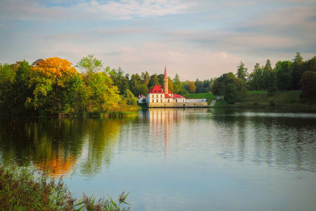 The beginning of autumn, the Priory Palace is reflected in the calm water. Beautiful landscape with Maltese Palace by the water. Gatchina.の写真素材