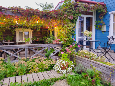 Cozy autumn terrace in the evening with decorative lighting and lots of flowers in pots. A quiet...