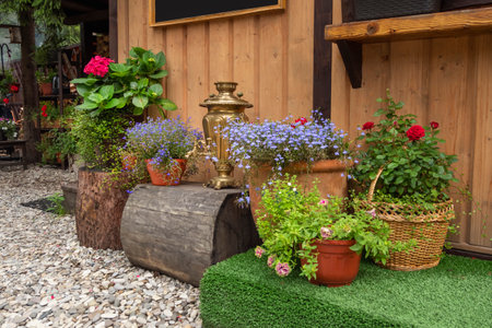 Garden scene in the summer. Summer garden with furniture, copper samovar and flowerpots with...