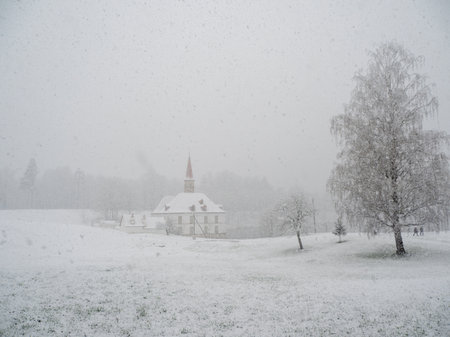 Photo view. Poor visibility. Spring snowfall. Sudden blizzard in the park. White snowy landscape with old palace in beautiful natural landscape.の写真素材