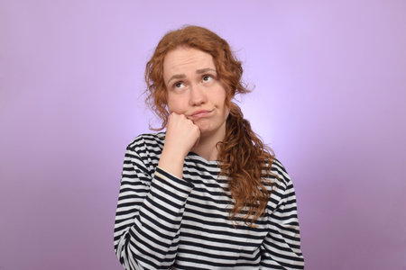 Young woman in striped pullover on purple background. Emotion conceptの写真素材