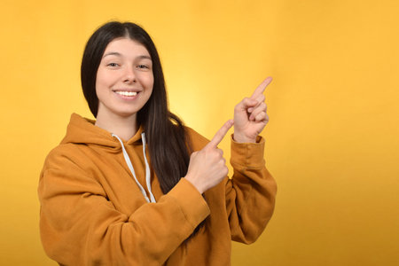 Young woman in yellow hoodie on yellow background. Copy space.の写真素材