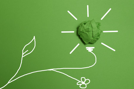 Green crumpled paper light bulb on green background, Corporate Social Responsibility. eco-friendly...