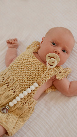 Newborn baby girl in a knitted dress with a pacifier
