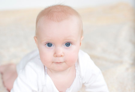 Portrait of adorable baby girl with blue eyes lying on the floor