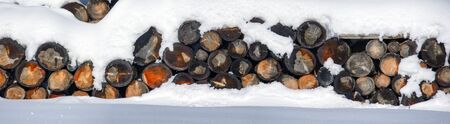 The logs woodpile in the snow in winter. Rural winter scene.