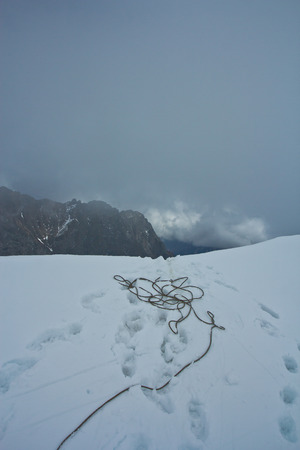 Rope for climbintg and steps of climbers in the top of snow mountain in bad wether in Altaj, Russia  at the winterの写真素材