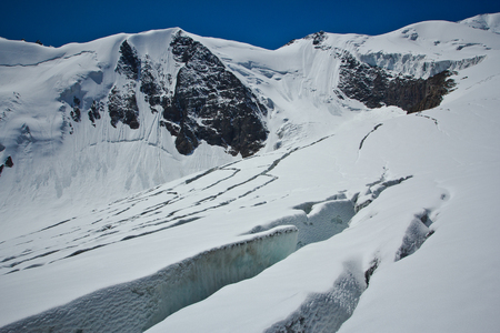 Cracks in the glacier with view to snow high mountains in the sunny day  in Altaj, Russia  at the summerの写真素材