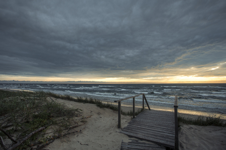 Dark sunset on the sea with waves from sand beach on the Curonian spit at the summerの写真素材