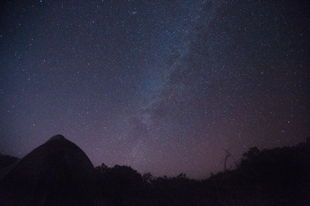 Milky way on the night sky above field with dark grass and tent, backgroundの写真素材