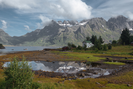 White house and mirror lake with view to snow mountains and sea in the Norway at summer timeの写真素材