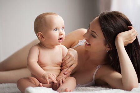 Young mother playing with her baby. She smiles and they are happy together.の写真素材