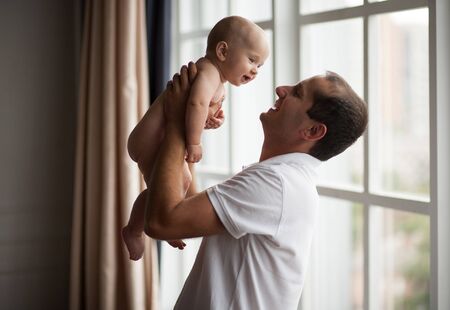 Small naked baby with his father. Father holds baby in his hands.の写真素材