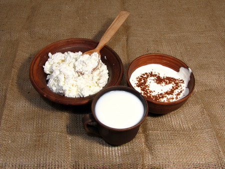Romantic breakfast with painted heart on Valentine's Day on jute background. Milk, cottage cheese and sour cream served in handmade old pottery. Heart is drawn from chocolate.                                の写真素材