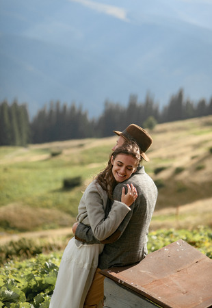 Newlyweds stand, smile and hug during honeymoon trip on background of Carpathian mountains.の写真素材
