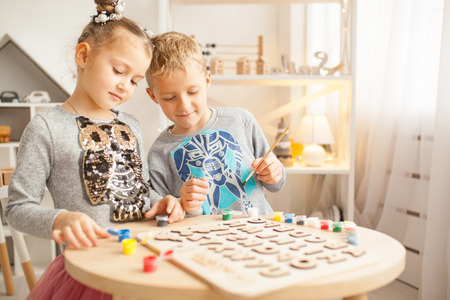 Preschooler girl and boy play and learn English letters using wooden alphabet.の写真素材