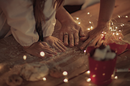 Top view to woman's and child's hands on the table powdered by flour on background of garland from light bulbs.の写真素材