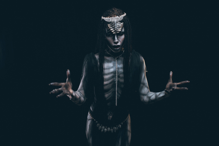 A young woman in the image of a humanoid and extraterrestrial alien with horns on her head and a pattern on the body like a reptile.の写真素材