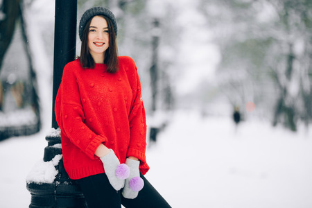 Pretty girl in red sweater during the walk on snowy street.の写真素材