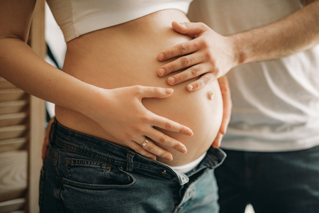 A man touches of the belly of his pregnant wife. Closeup.の写真素材