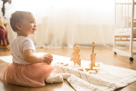 Toddler girl sits on the mat and plays in the nursery.の写真素材