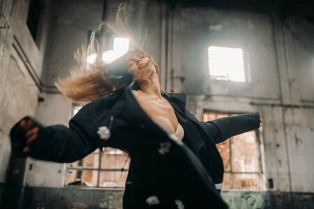 Young lonely seminude woman stands in the middle of an abandoned and destroyed building.の写真素材