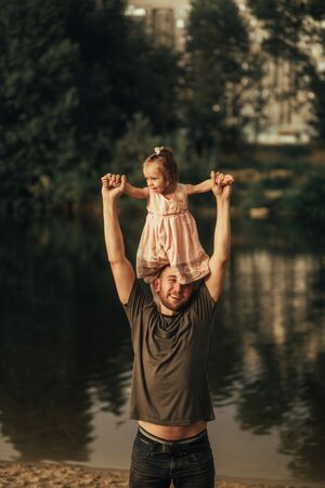 Father with his little daughters is on the walk next to the lake.の写真素材