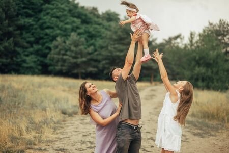 Happy family has fun on a walk and throws up their little daughter in the forest.の写真素材
