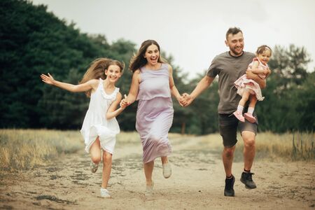 Happy family with two children has fun, runs and laughs joyfully on a walk in the forest.の写真素材