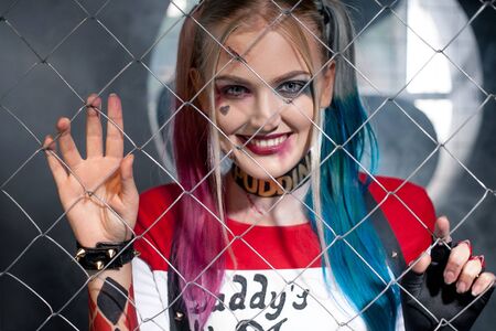 Dnipro, Ukraine - August 17, 2016: Portrait of smiling girl in costume Harley Quinn. She looks through the grid. Close up. Cosplay.のeditorial素材