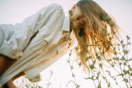 Portrait of happy young woman among meadow herbs on sky background.の写真素材