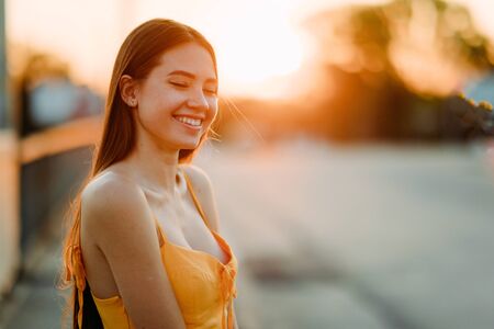 Portrait of a young woman with loose long hair in a yellow dress at sunset.の写真素材