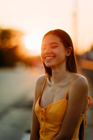 Portrait of a young woman with loose long hair in a yellow dress at sunset.の写真素材